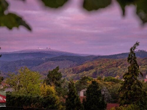 Sonnenaufgang im Herbst mit Schnee auf dem Brocken und bunter Laubfärbung in Wernigerode.